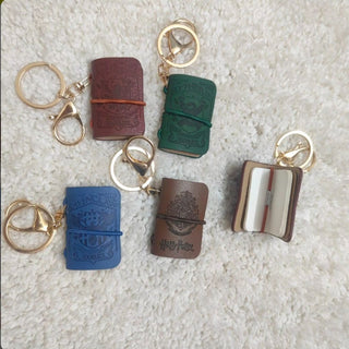 Set of small leather Harry books with gold keychains on a textured surface